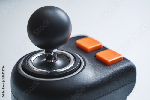 Close up of a black joystick with an orange button  suggesting gaming or control.