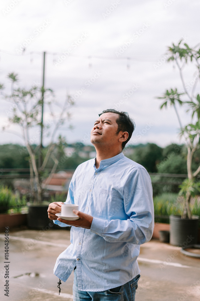Fototapeta premium A Southeast Asian man enjoying a cup of coffee in the morning