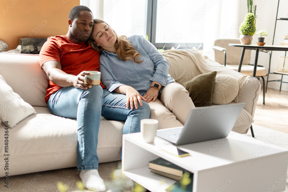 African American man with coffee watching film on laptop while woman sleeping near him African American man with coffee watching film on laptop while woman sleeping near him