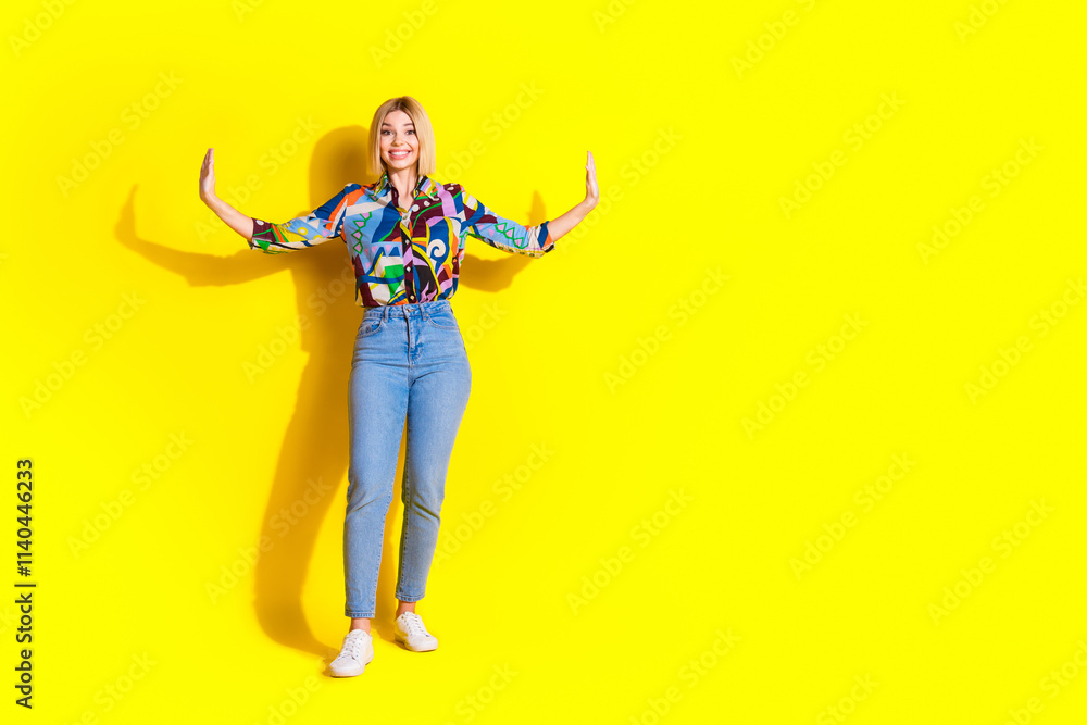 Full size photo of pretty young girl push side walls empty space wear trendy colorful outfit isolated on yellow color background Full size photo of pretty young girl push side walls empty space wear trendy colorful outfit isolated on yellow color background