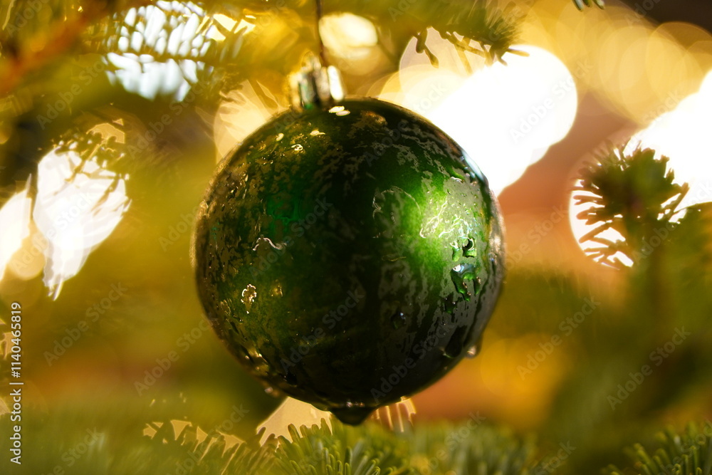 A green Christmas ornament hanging from a tree A green Christmas ornament hanging from a tree