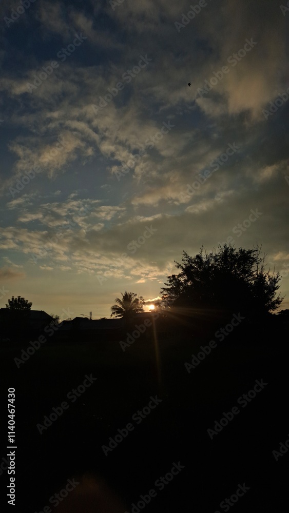 The sun sets in winter behind a house in the countryside. The sun sets in winter behind a house in the countryside.