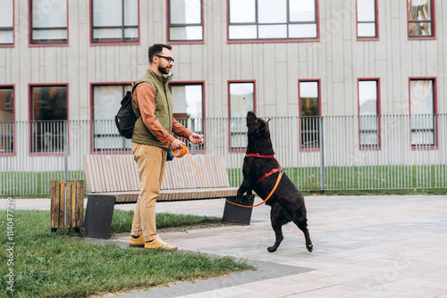 Happy, handsome Latin man wearing casual clothes, pet owner playing with dog, black labrador photo