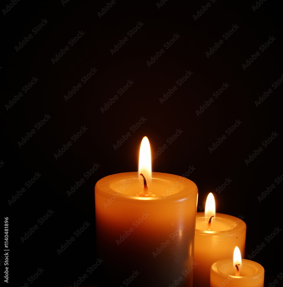 Three lit candles glowing in darkness Three lit candles glowing in darkness