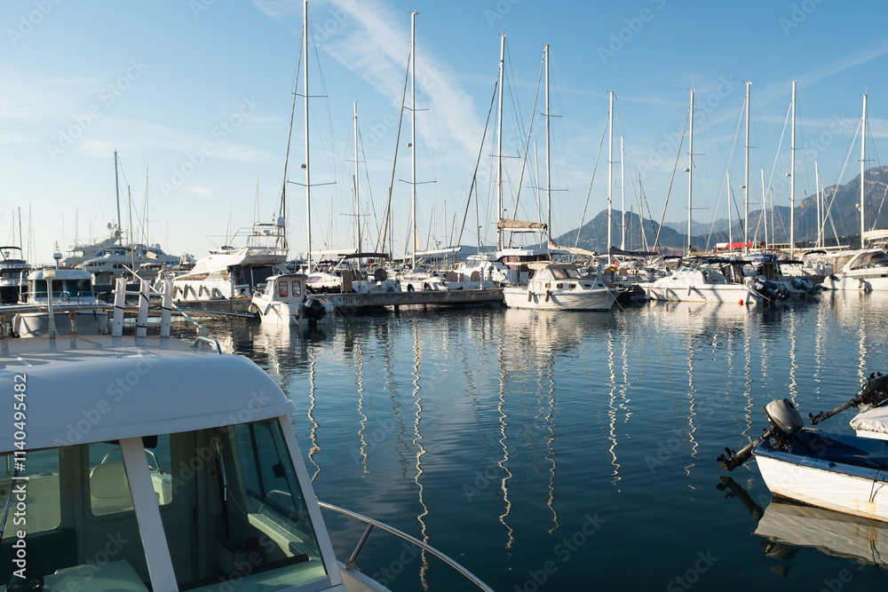 Fototapeta premium Picturesque Harbor with Boats and Mountain Village. The calm water reflects the surrounding architecture and hills, creating a peaceful coastal atmosphere. High quality photography