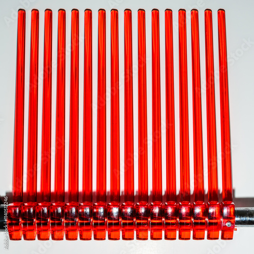 Abstract view of rows of red acrylic rods from a pasta drying rack on a white background. photo