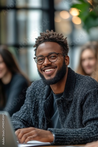 Young man smiling during a group study session in a modern cafe setting