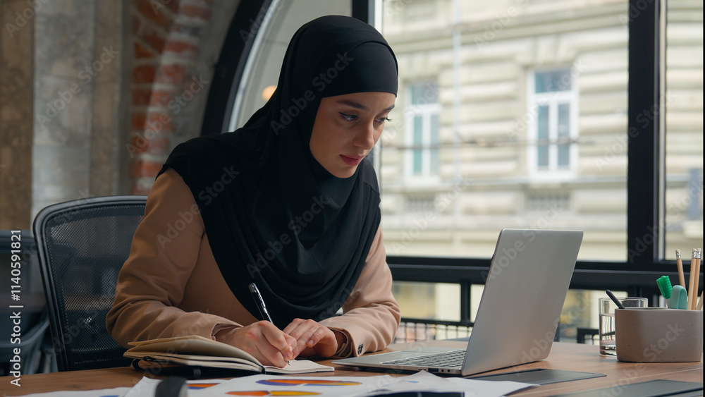 Muslim busy concentrated Islamic woman Arabian girl business analyst female worker manager work papers documents diagram colorful stats designer businesswoman in hijab writing using laptop in office Muslim busy concentrated Islamic woman Arabian girl business analyst female worker manager work papers documents diagram colorful stats designer businesswoman in hijab writing using laptop in office