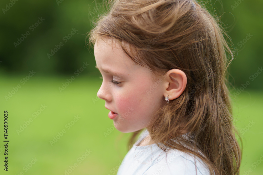 Little red-haired cute girl in summer outdoors in park. Concept of active healthy child in nature