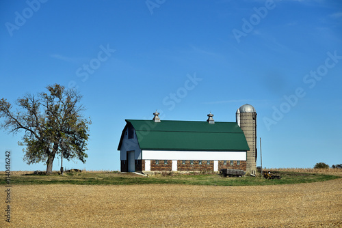 An unusually structured barn with brick paneling sits beyond a harvested cornfield along with a lone tree in rural north central Illinois as autumn descends on the area.
