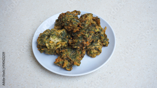 A plate of fried bakwan made from spinach with green color