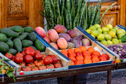 A table full of fresh fruits and vegetables, including tomatoes, oranges