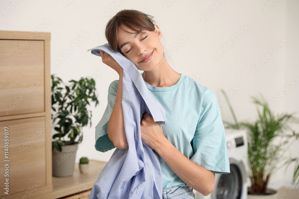 Happy young woman with clean shirt in laundry room Happy young woman with clean shirt in laundry room