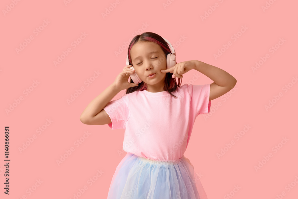 Cute little Asian girl in headphones on pink background Cute little Asian girl in headphones on pink background