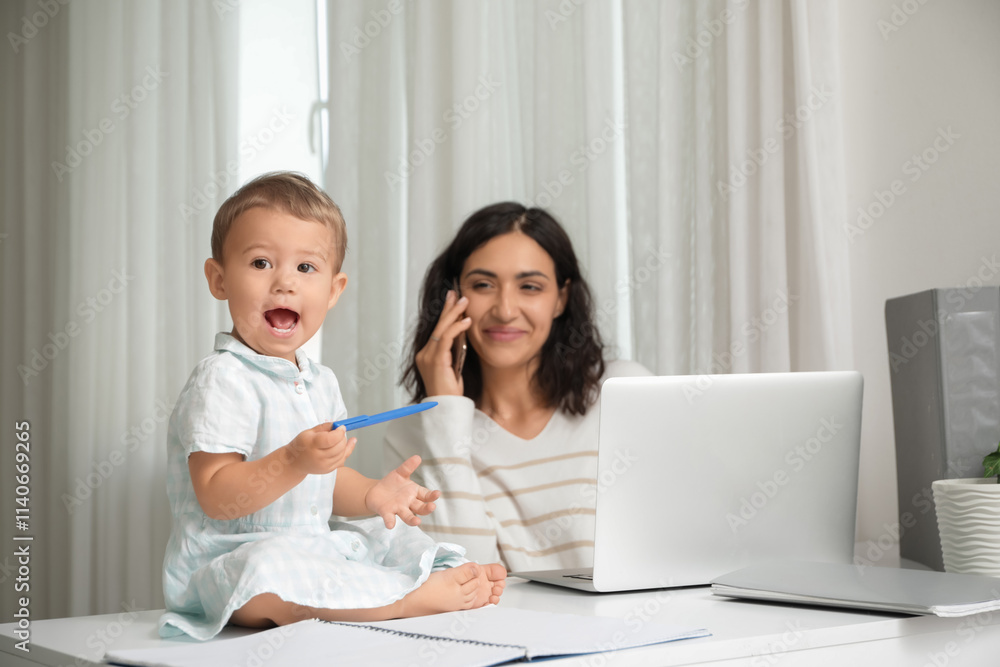 Working mother and her little baby with pen on table at home Working mother and her little baby with pen on table at home