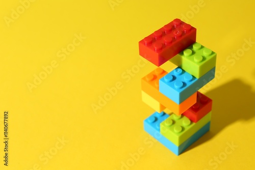 Construction toy. Figure made with building bricks on yellow background, space for text