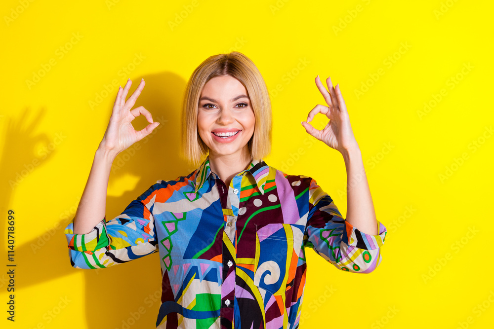Photo portrait of lovely young lady show okey approve dressed stylish colorful garment isolated on yellow color background Photo portrait of lovely young lady show okey approve dressed stylish colorful garment isolated on yellow color background