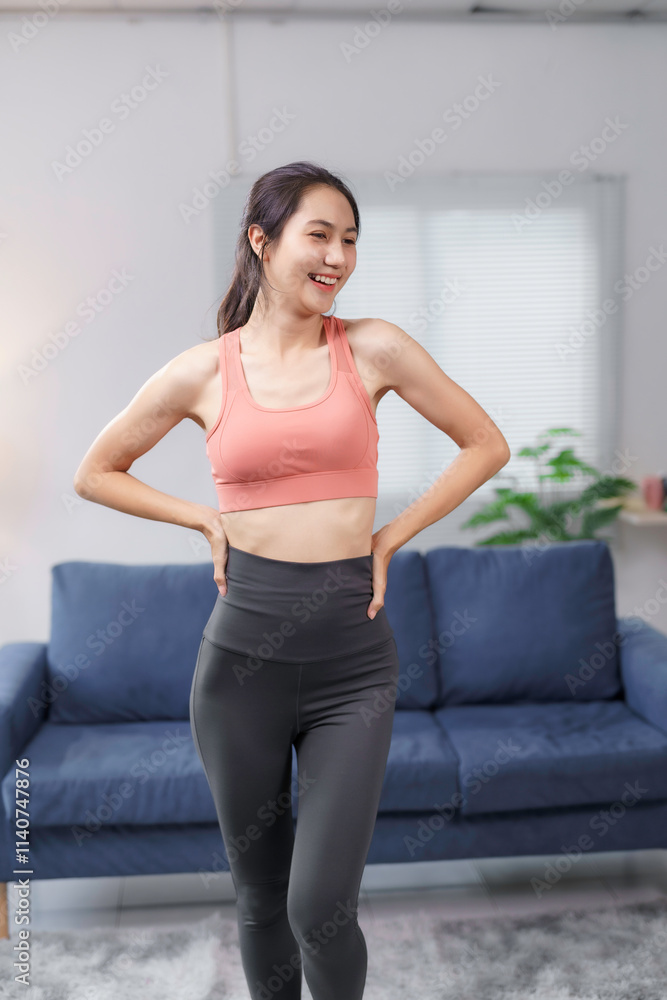 Fit asian woman smiling and enjoying a home workout, wearing stylish sportswear while engaging in her fitness routine in a cozy living room Fit asian woman smiling and enjoying a home workout, wearing stylish sportswear while engaging in her fitness routine in a cozy living room
