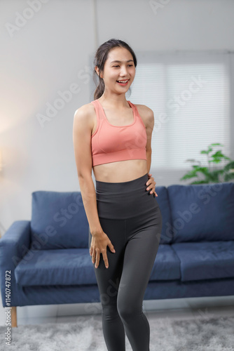 Fit asian woman wearing sportswear, smiling and doing fitness exercises in her living room