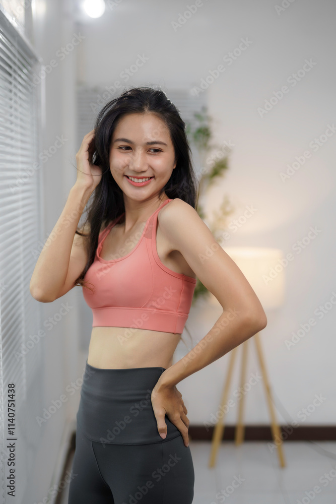 Confident woman in sportswear smiling and posing in a bright indoor setting with modern decor, embodying health, fitness, and positivity Confident woman in sportswear smiling and posing in a bright indoor setting with modern decor, embodying health, fitness, and positivity