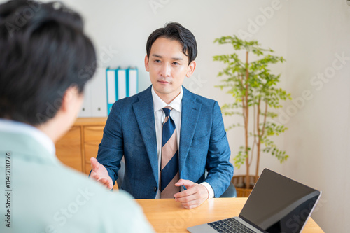 パソコンを使って打ち合わせをするスーツと作業服の男性 photo