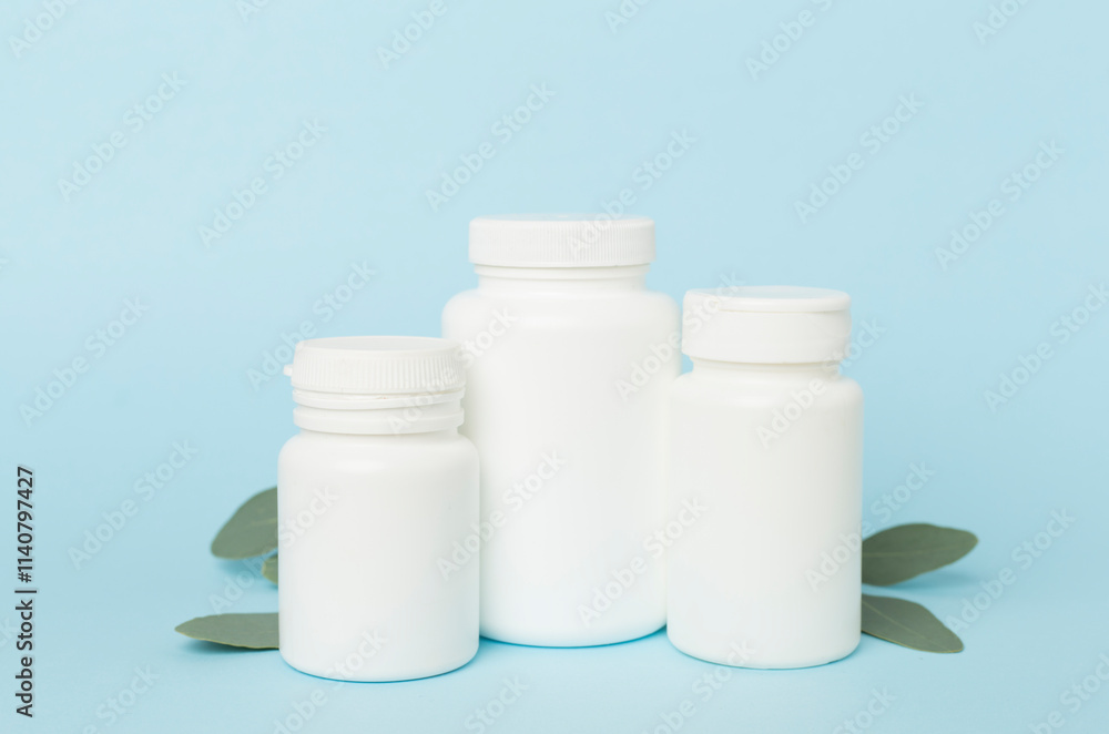 Bottles with pills and green leaves on color background Bottles with pills and green leaves on color background