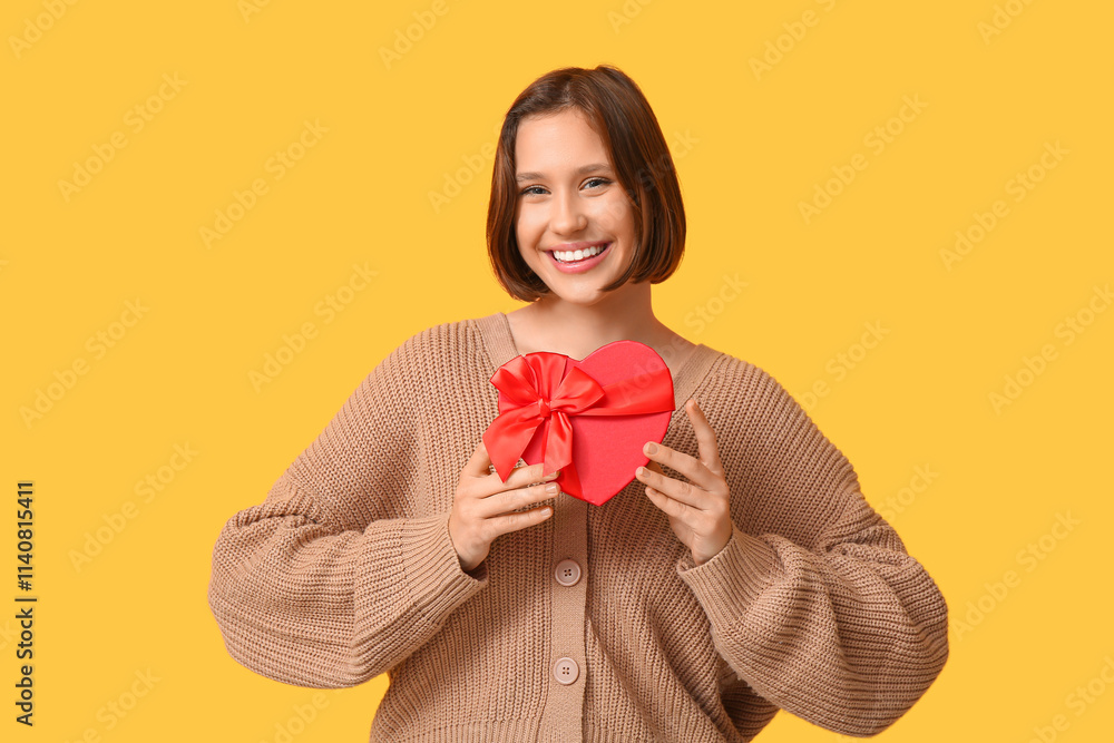 Beautiful young woman with gift box on yellow background. Valentine's Day celebration Beautiful young woman with gift box on yellow background. Valentine's Day celebration