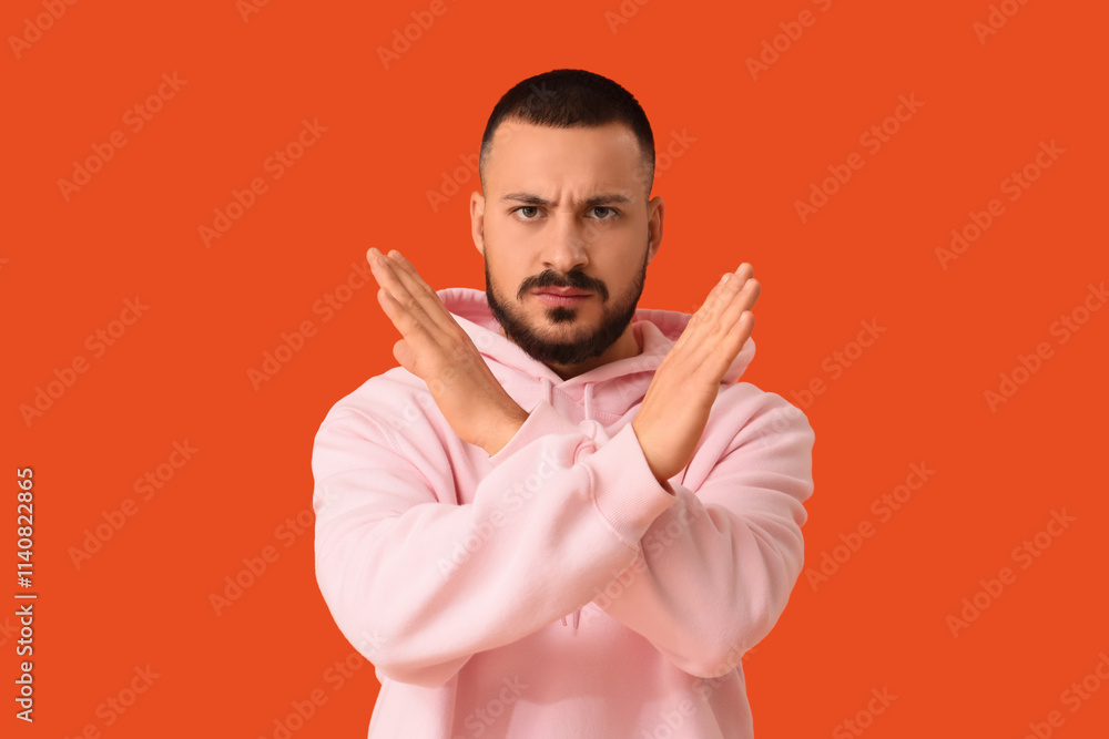 Young man showing STOP gesture on orange background. Rules concept Young man showing STOP gesture on orange background. Rules concept