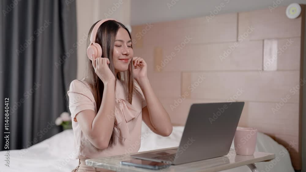 Asian women working at home, sitting in corner at front desk in bedroom, picking up headphones listen music relax, while working avoid causing too much stress, swaying, humming soft tune with comfort. Asian women working at home, sitting in corner at front desk in bedroom, picking up headphones listen music relax, while working avoid causing too much stress, swaying, humming soft tune with comfort.