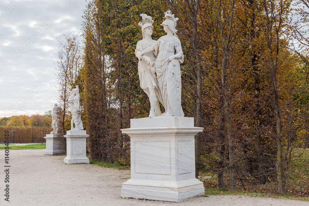Garden alley with white stone sculptures in autumn park Garden alley with white stone sculptures in autumn park