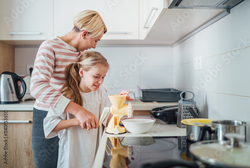 Mother and daughter enjoy cooking session together in modern kitchen sharing togetherness time and bonding over meal preparation. Mother and kid relations and home sweet home concept image.