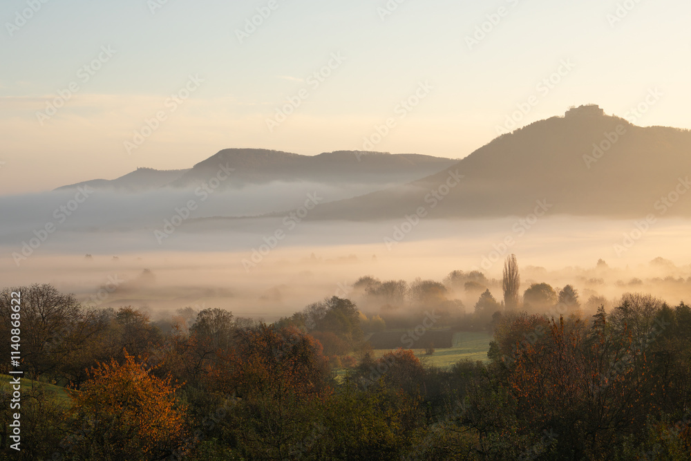Blick auf die Burgfestung Hohenneuffen mit dem Albtrauf im Nebel zum Sonnenaufgang. Schwäbischen Alb im Herbst. Blick auf die Burgfestung Hohenneuffen mit dem Albtrauf im Nebel zum Sonnenaufgang. Schwäbischen Alb im Herbst.