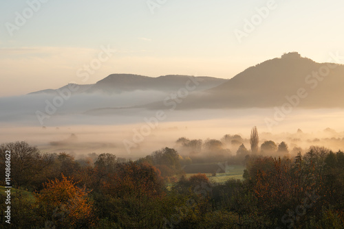 Blick auf die Burgfestung Hohenneuffen mit dem Albtrauf im Nebel zum Sonnenaufgang.  Schwäbischen Alb im Herbst.  photo