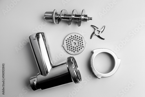 Assorted Metal Components of a Kitchen Meat Grinder Disassembled on White Surface