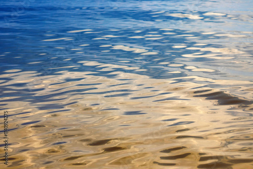 Abstract background of the water surface in the reflections of the golden rays of the sun. Reflection of light.Ripples and waves