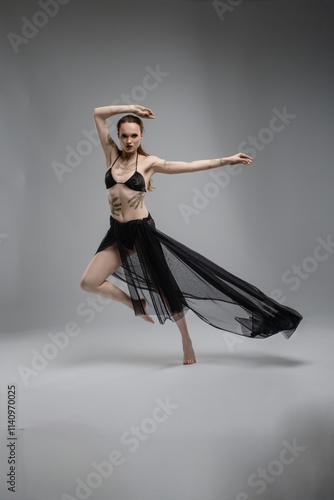 Bild auf Leinwand Elegant dancer performing a graceful pose against a neutral background