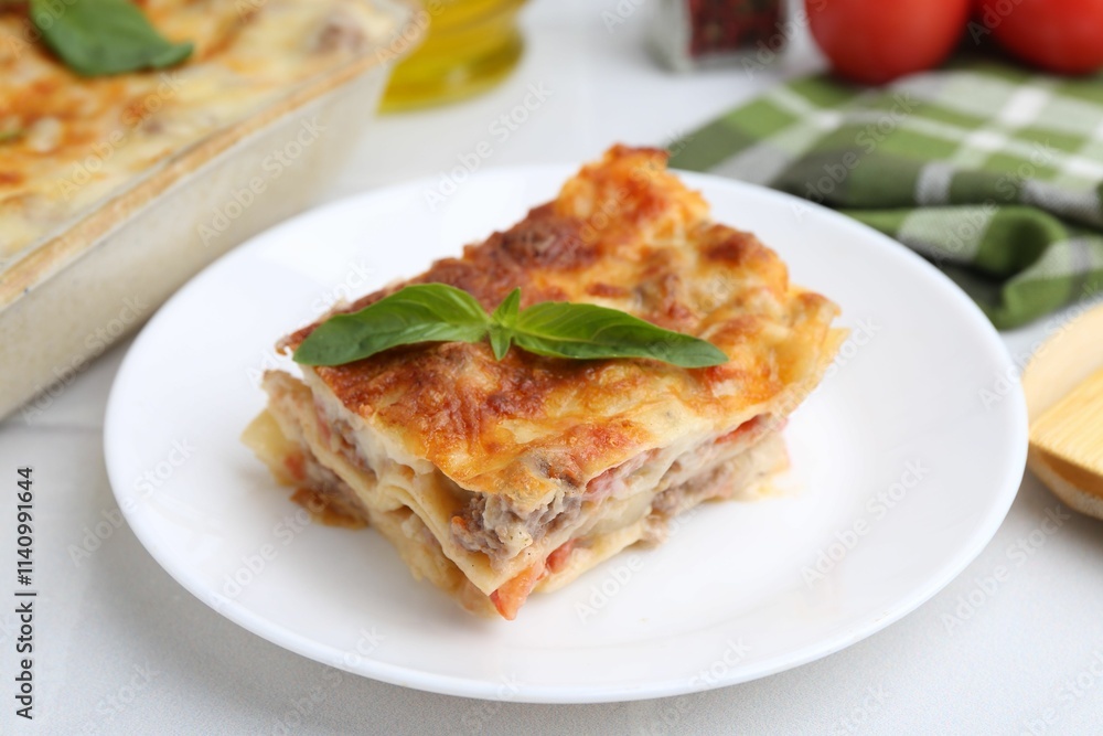 Piece of delicious cooked lasagna with basil on white table, closeup Piece of delicious cooked lasagna with basil on white table, closeup
