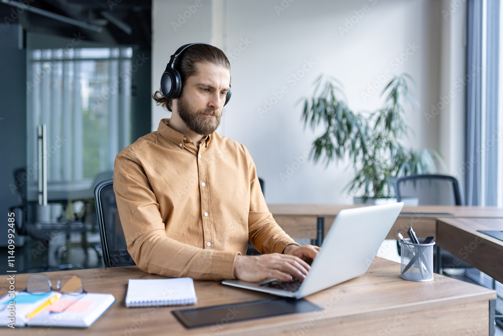 Focused business professional wearing headphones and working diligently on a laptop in an office. The image portrays concentration, productivity, and a professional work environment Focused business professional wearing headphones and working diligently on a laptop in an office. The image portrays concentration, productivity, and a professional work environment