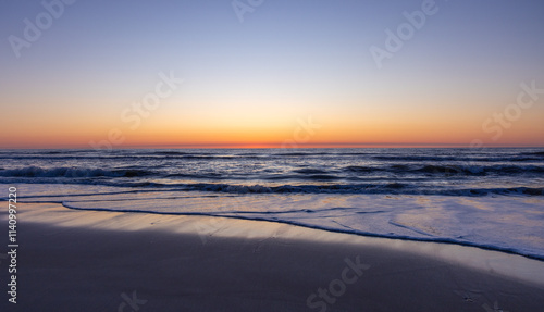 Gentle waves lap up on the shore of the Outer Banks at dawn