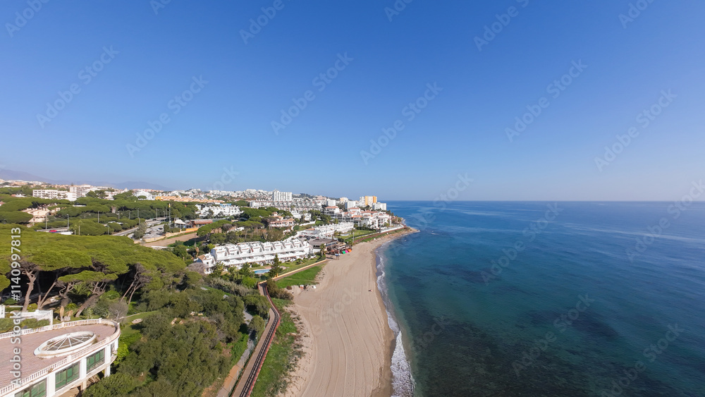 Aerial drone photo of the beautiful beach front in the town of Sitio de Calahonda in Mijas Spain showing the sandy beach and front side apartments from above in the month of December on a sunny day Aerial drone photo of the beautiful beach front in the town of Sitio de Calahonda in Mijas Spain showing the sandy beach and front side apartments from above in the month of December on a sunny day