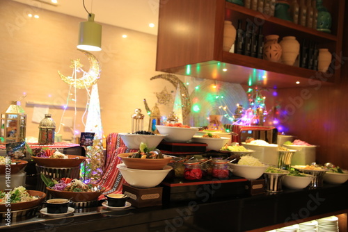 A vibrant buffet setup showcasing a variety of colorful dishes, elegantly arranged with festive decor and twinkling lights, creating a warm and inviting atmosphere for dining