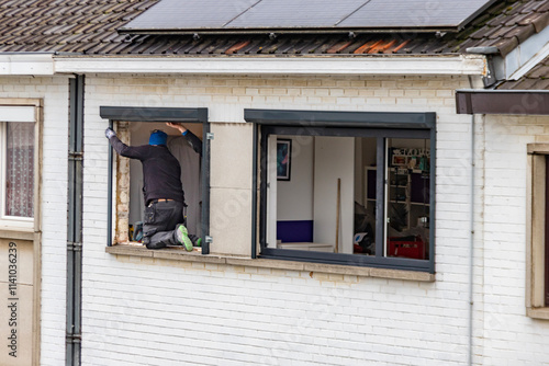 Ouvrier qui remplace un châssis de fenêtre à une maison