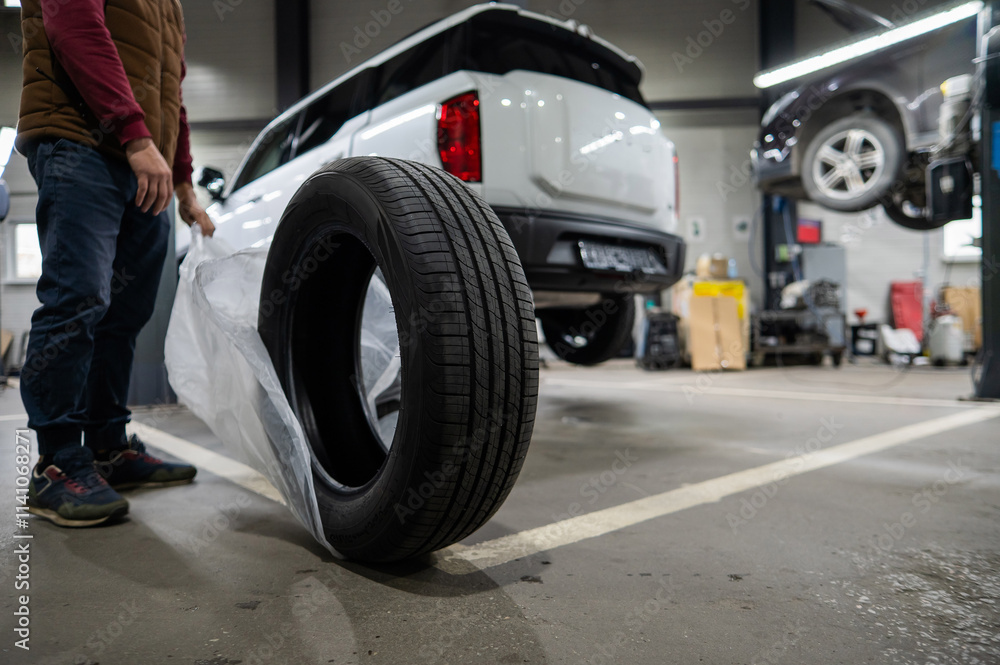 Mechanic unpacking new tires in a garage. Mechanic unpacking new tires in a garage.