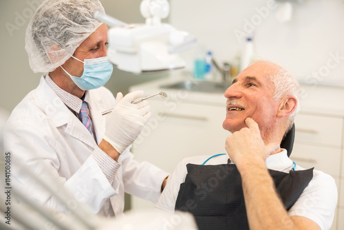 Adult male doctor dentist examining teeth of elderly male patient before treatment in office