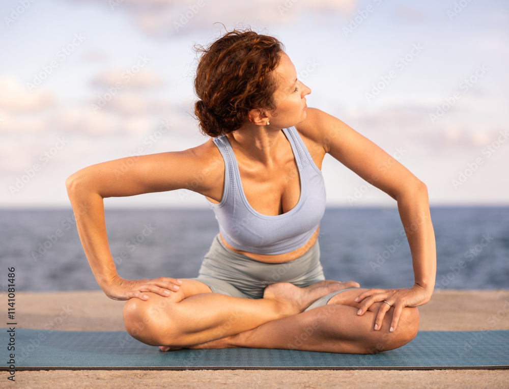 Experienced female trainer doing various exercises to warm up the body before yoga classes on the seashore Experienced female trainer doing various exercises to warm up the body before yoga classes on the seashore