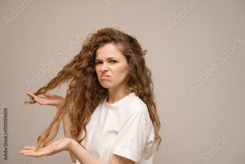 Tableau sur toile A frustrated, dissatisfied young woman touching ends of her hair and is horrified by the dry, damage and unruly hair and split ends of dry hair