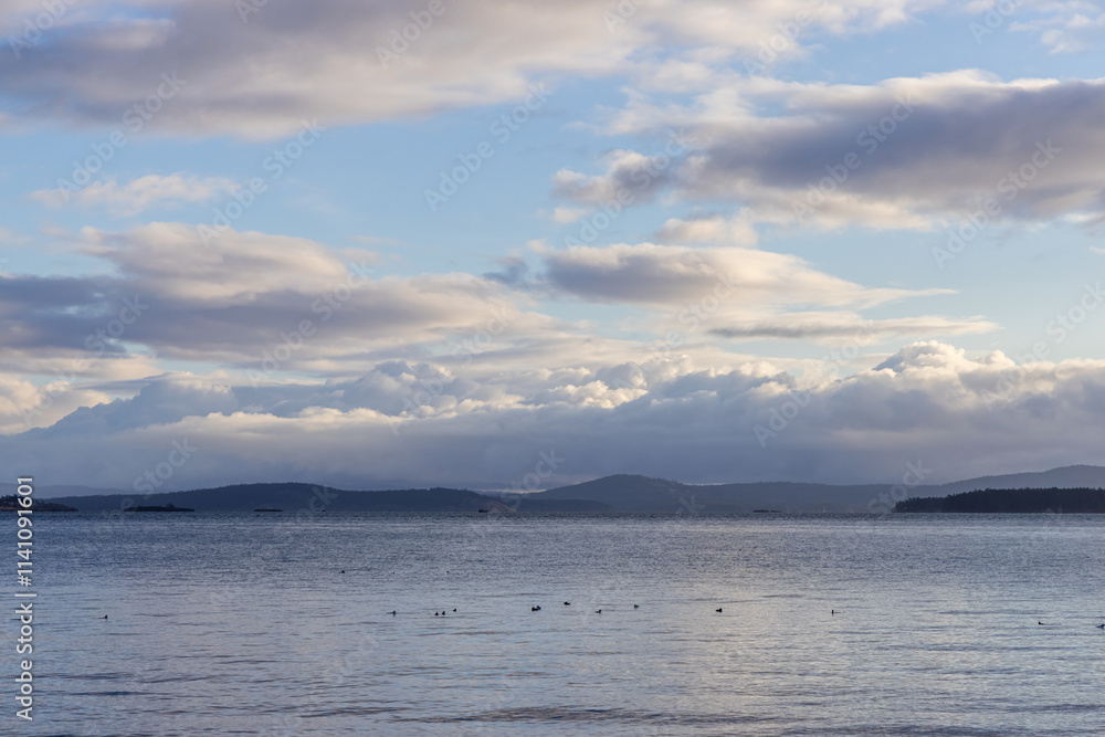 Peaceful Coastal Sunrise Over the Ocean With Cloudy Sky and Hills in Distance Peaceful Coastal Sunrise Over the Ocean With Cloudy Sky and Hills in Distance