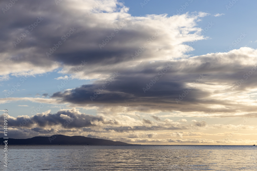 Scenic Coastal Landscape With Dramatic Clouds Over Calm Ocean Waters Scenic Coastal Landscape With Dramatic Clouds Over Calm Ocean Waters