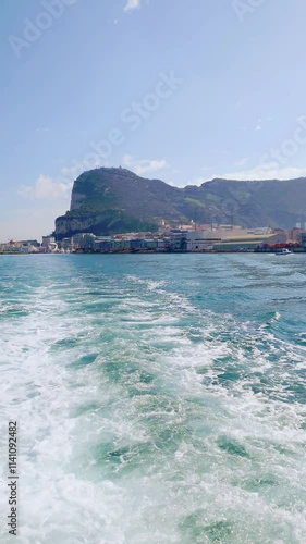 Scenic view of Gibraltar marina with the iconic Rock of Gibraltar in the background, modern waterfront buildings, and calm turquoise waters