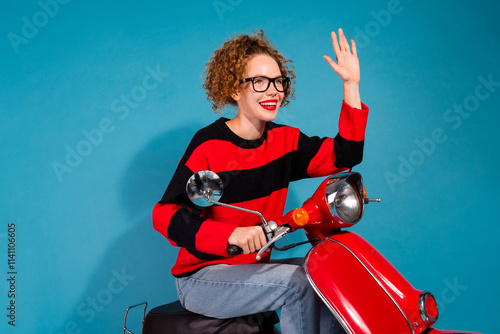 Happy woman on red scooter waving with blue background